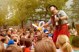 Clown Herr Balzer spielt Kindertheater mit Luftballontieren und Akkordeonmusik, hier im Garten des jüdischen Museums Berlin.